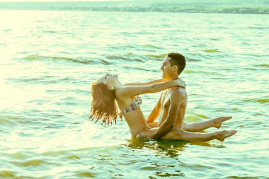 Gün batımında suda duran iki genç yetişkin aşıklar 