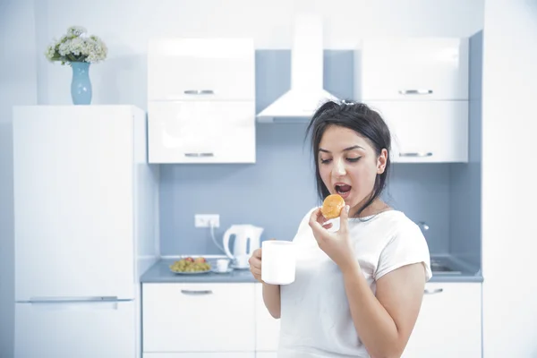 Mujer joven comiendo pastel en la cocina — Foto de Stock