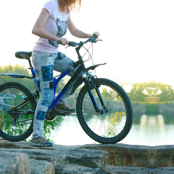 Mujer joven parada cerca de la bicicleta — Foto de Stock