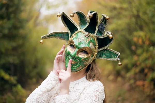 Portrait of Beautiful woman in green carnival mask with metal bells. woman with silence gesture