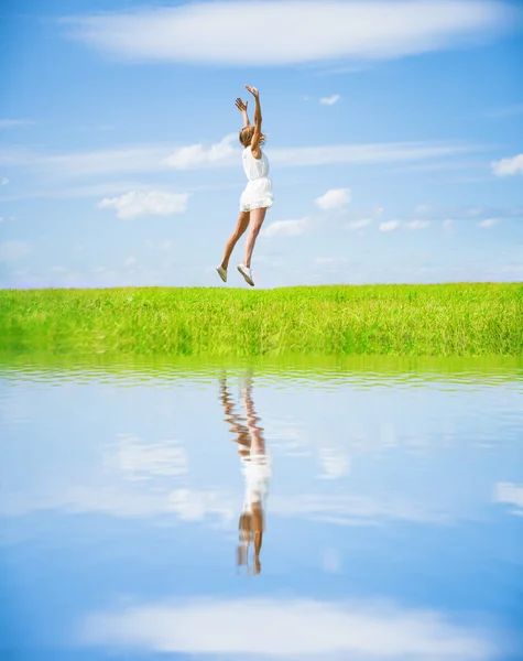 Jumping žena v zeleném poli — Stock fotografie