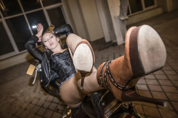 专注于棕色皮鞋 性感的女孩躺在摩托车拱门在黑暗的房间 — 图库照片