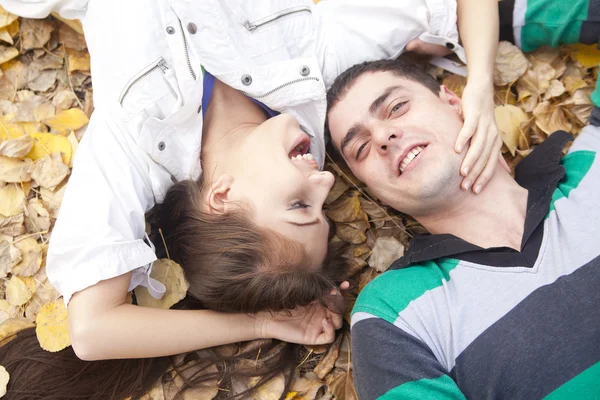 合上快乐的拉丁裔西班牙情侣的肖像在秋季公园的干燥的黄色秋天叶子亲吻和拥抱谎言 — 图库照片