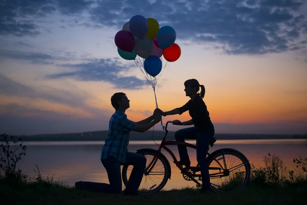 Mulher na bicicleta e homem segurando balões — Fotografia de Stock