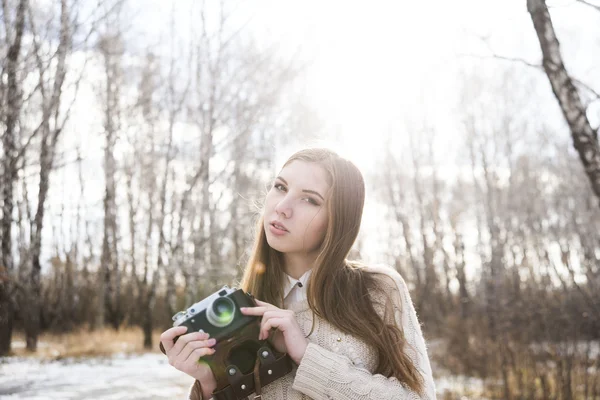 美丽的年轻女孩的肖像拍照与老式复古相机在冬季树木和雪背景 — 图库照片