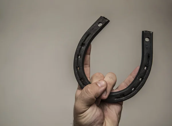 fingers holding  new iron horseshoe