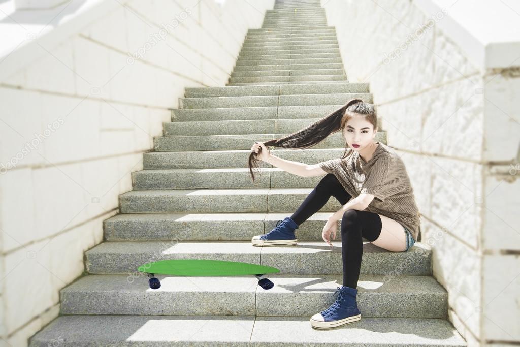 girl sitting with  green skateboard