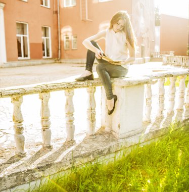 Vintage çit oturan ve gönüllülük a kitap kırmızı bina karşı ciddi kız 