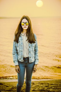 Muhteşem casual esmer güzel bir vahşi kum plajı üzerinde poz. Günbatımı 