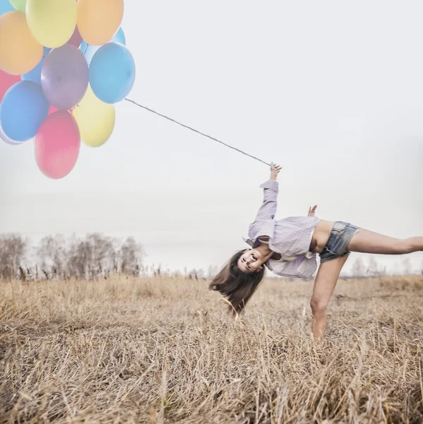Frau springt mit Luftballons — Stockfoto