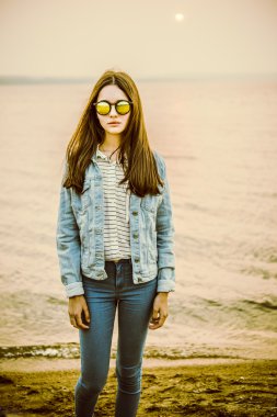 Muhteşem casual esmer güzel bir vahşi kum plajı üzerinde poz. Günbatımı 