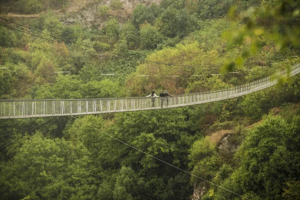 Couple walking on suspension bridge in mountains — Stock Photo, Image
