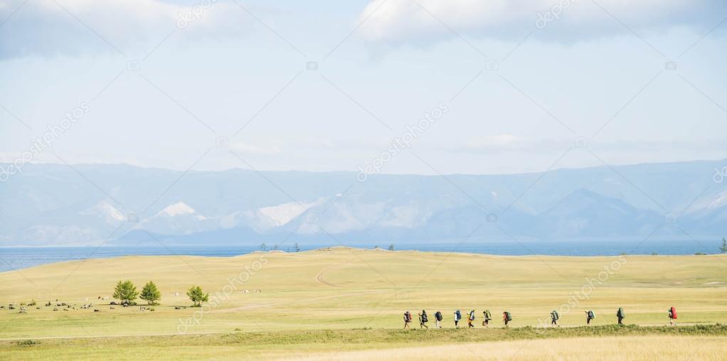group of hikers going along horizon in mountains