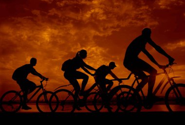Boşluk. Gün batımında bisiklete binen sportif arkadaşlar. Bisikletçiler sahil boyunca gidiyor. Doğa arka planında spor.