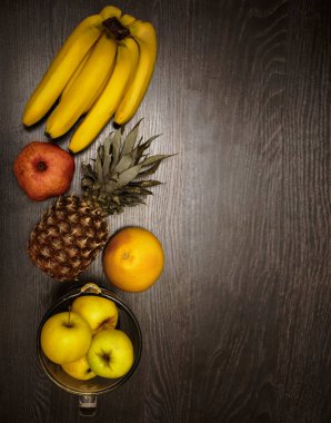 Elma, bir ananas, greyfurt, nar ve taze muz. Üst Manzara. Siyah ahşap masa arka planı. Boş kopya alanı. sıra sağlıklı yiyecekler