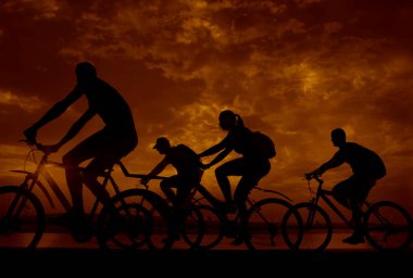 Boşluk. Gün batımında bisiklete binen sportif arkadaşlar. Bisikletçiler sahil boyunca gidiyor. Doğa arka planında spor.