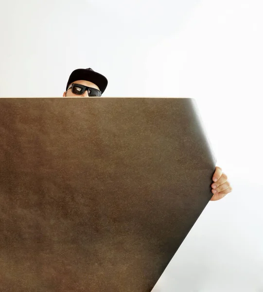 白い壁の背景に黒い壁紙のロールを持つ男性インテリアデザイナー ハンドクラフト紙ロールを持つ男デザイナー 碑文のための空のコピースペース — ストック写真