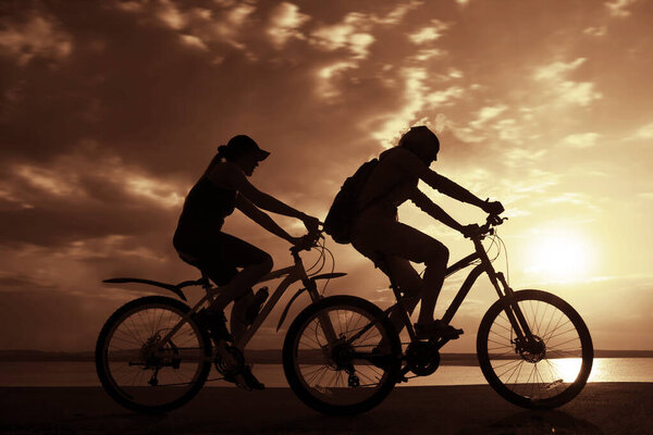 Empty Space. Sporty friends on bicycles on sunset.  cyclists riding along coast. Sport on Nature background.