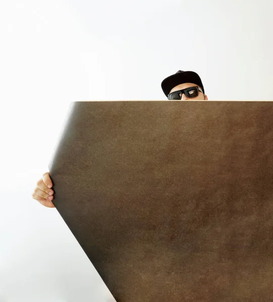 白い壁の背景に黒い壁紙のロールを持つ男性インテリアデザイナー クラフト紙のロールを持つ男デザイナー 碑文のための空のコピースペース — ストック写真