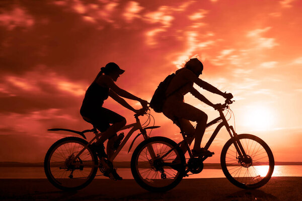 Empty Space. Sporty friends on bicycles on sunset.  cyclists riding along coast. Sport on Nature background.