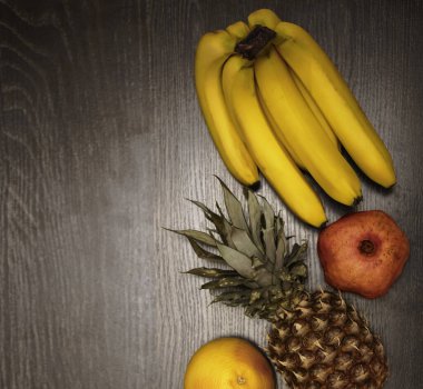  Bir ananas, greyfurt, nar ve taze muz. Üst Manzara. Siyah ahşap masa arka planı. Boş kopya alanı. sıra sağlıklı yiyecekler