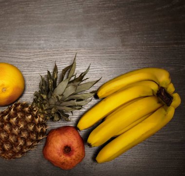  Bir ananas, greyfurt, nar ve taze muz. Üst Manzara. Siyah ahşap masa arka planı. Boş kopya alanı. sıra sağlıklı yiyecekler