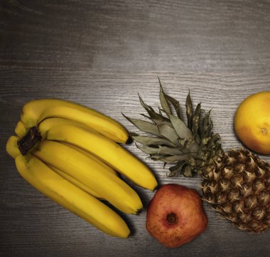  Bir ananas, greyfurt, nar ve taze muz. Üst Manzara. Siyah ahşap masa arka planı. Boş kopya alanı. sıra sağlıklı yiyecekler