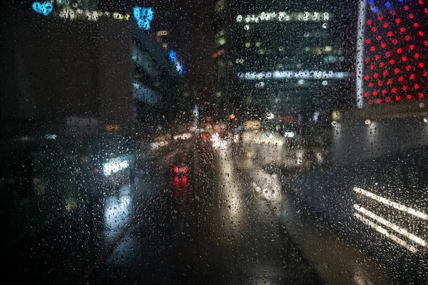 Drops Of Rain On Glass Background. Street  Bokeh Lights Out Of Focus.  Abstract Backdrop. Rainy night.