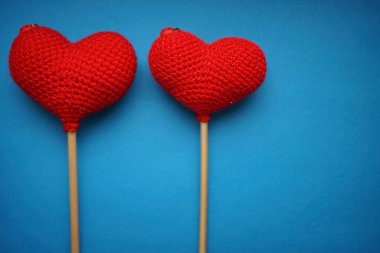 Mavi arka planda iki kırmızı yünlü kalp. Sevgililer günün kutlu olsun..