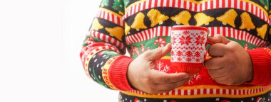 Sıcak çikolata içen bir adam. Noel ağacı deseni. Madalyalı içki kupası. Erkek, kırmızı fincanda sıcak kahve tutan örgü süveter ve Xmas süsü giyiyor. Eşcinseller kış tatillerini kutlar. Yüzü yok