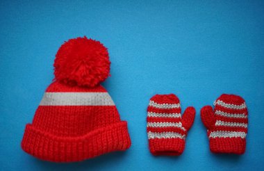 Mavi arka planda örülmüş kış şapkası ve bir çift eldiven. Üst Manzara. Düz yatıyordu. Noel arkaplanı