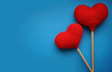 Mavi arka planda izole edilmiş iki kırmızı örülmüş kalp. Sevgililer günün kutlu olsun..