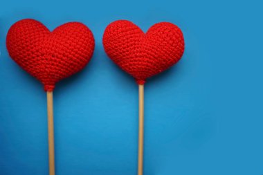 Mavi arka planda iki kırmızı yünlü kalp. Sevgililer günün kutlu olsun..