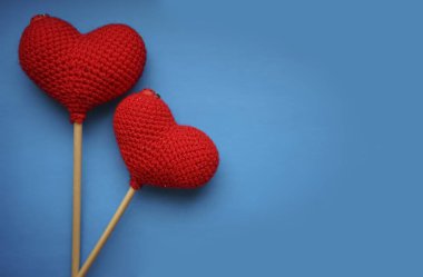 Mavi arka planda izole edilmiş iki kırmızı örülmüş kalp. Sevgililer günün kutlu olsun..