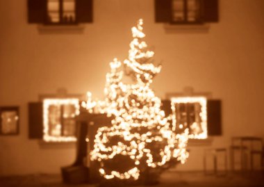 Noel ışıkları olan bir evin arka planında Noel süsleri olan ladin dalları. Evin ön cephesinde Noel süsleri. Bulanık arkaplan