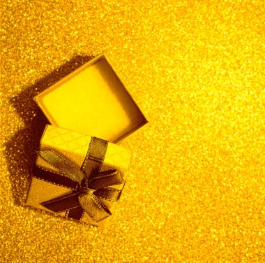 Altın masanın üzerinde kahverengi kurdele olan boş sarı hediye kutusunu aç. Üst Manzara. Odaklanmamış bokeh arkaplanı