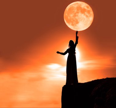 Dağın tepesinde duran bir kadın silueti. Dişi, kafasının üstünde dolunaya dokunuyor. arka plan ve ay ışığı. iyi titreşimler