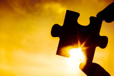 Sunset arkaplanlı yapboz parçalı el..