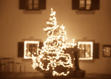 Noel ışıkları olan bir evin arka planında Noel süsleri olan ladin dalları. Evin ön cephesinde Noel süsleri. Bulanık arkaplan