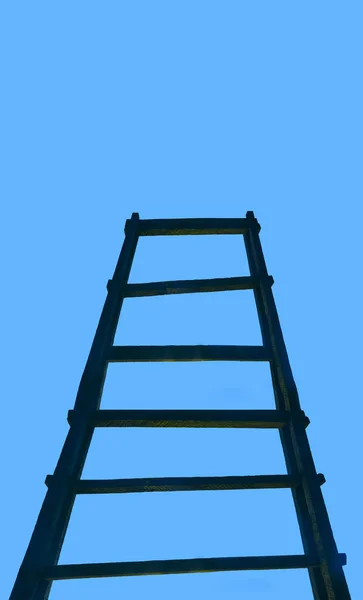 Old wooden ladder leading to a cloud in blue sky. aged Stairway to Heaven. Road To Success. Achievement Of Goals Career Metaphor