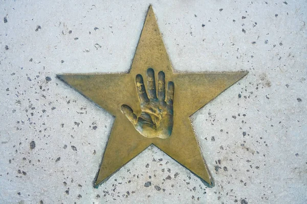 Hand print in golden star. concrete background.