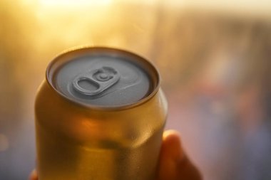 Güneşli bir günde altın bira kutusu kapanıyor. Sıcak bir günde taze bir içki. Metalik kutu ve soğuk içecek. Alkol içeceği. ıslak yüzey.