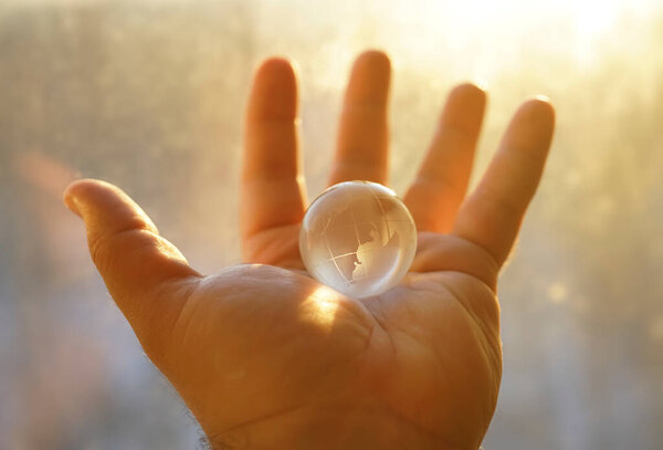 transparent glasses Globe in male hand against sunny sky. Environmental protection concept. sunlight.