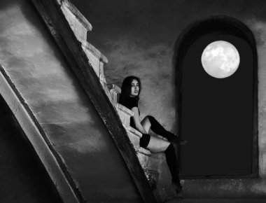 Güzel Latin dansçı kadın merdivenlerde dinleniyor. Siyah elbiseli genç kız beton merdivenlerde oturuyor.