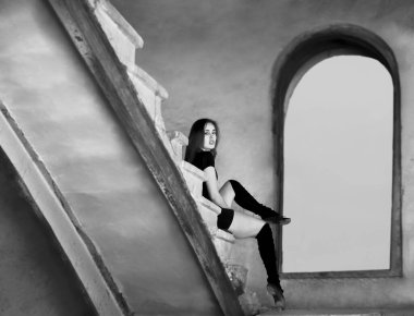 Güzel Latin dansçı kadın merdivenlerde dinleniyor. Siyah elbiseli genç kız beton merdivenlerde oturuyor.