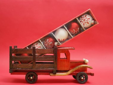 Kırmızı kağıt arka planda el yapımı oyuncak kamyonet. Noel oyuncakları kutuda. Mutlu yıllar ve mutlu Noeller..