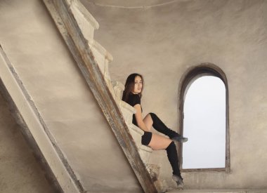 Güzel Latin dansçı kadın merdivenlerde dinleniyor. Siyah elbiseli genç kız beton merdivenlerde oturuyor.