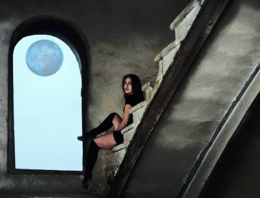 Güzel Latin dansçı kadın merdivenlerde dinleniyor. Siyah elbiseli genç kız beton merdivenlerde oturuyor.