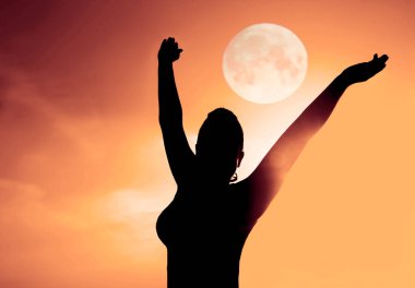 Ellerini kaldırmış bir kadın silueti. Başının üstünde ve kollarının arasında dolunay..