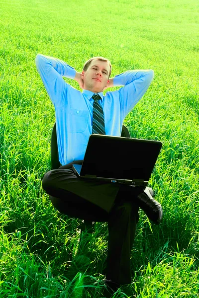 現場のビジネスマンだノートパソコンを持ってる 幸せで成功した 緑の芝生の畑で椅子に座っているビジネスマン 目を閉じて — ストック写真